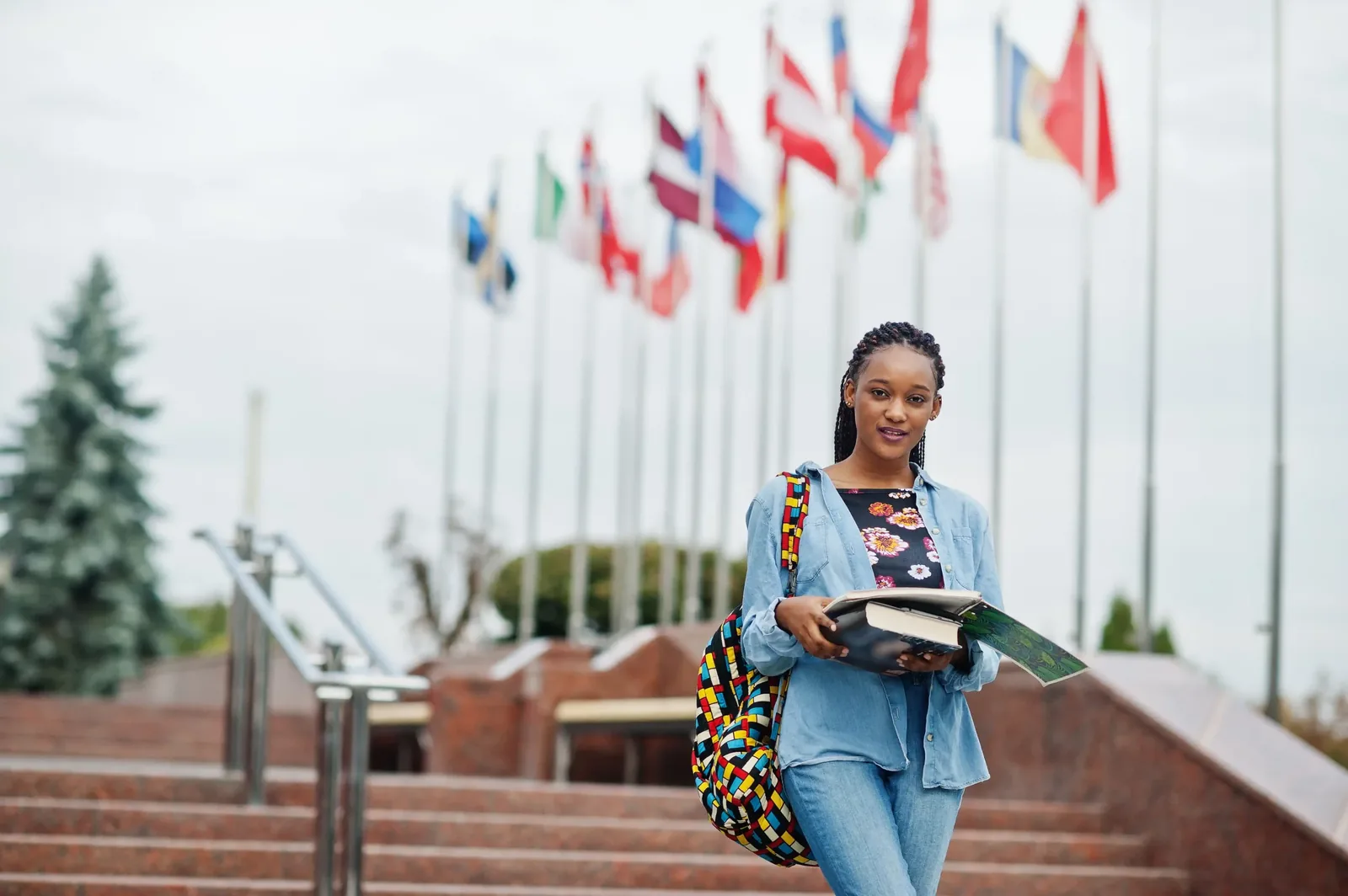 Étudiante africaine sur le campus, devant les drapeaux de différents pays
